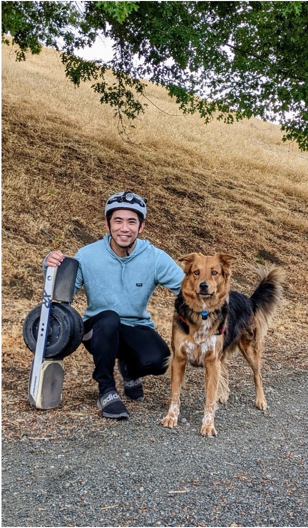 An image of Ryan Lee with his dog and his skateboard.